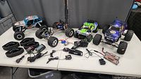 Overview of three RC vehicles, spare wheels, track kits, transmitters, chargers and battery pack on table
