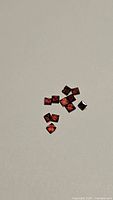 Photo of natural Mozambique garnet gemstones, square cut, on a plain background.