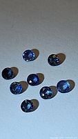 Photo showing eight small round cut blue sapphire gemstones with good clarity and color.