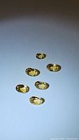 Six natural golden citrine oval cut gemstones displayed on a white background under light showing clarity and color.