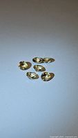 Five small oval cut natural golden citrine gemstones on white background showing size and color