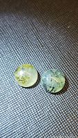 Two round moss agate cabochons approximately 10mm diameter with visible moss-like inclusions under bright light.