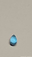Fancy briolette cut natural blue topaz gemstone showing facets and drilled hole for jewelry making