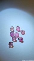 Photo showing 10 small natural pink tourmaline stones with visible inclusions and varying pink hues on a plain light background.