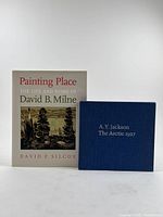 Front view of two books: "Painting Place: The Life and Work of David B. Milne" with beige dust jacket and "A.Y. Jackson The Arctic 1927" with blue cloth cover.