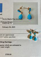 Pair of turquoise drop earrings on appraisal certificate background