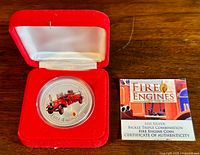 Silver coin in red velvet box with Certificate of Authenticity beside it