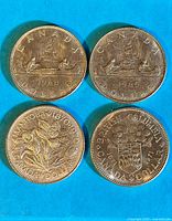 Top view of four Canadian silver dollar coins depicting provincial designs and voyageur canoe scene, showing dates 1968, 1870 (Manitoba Centennial), and 1971 (British Columbia Centennial).