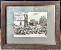 Framed vintage black and white photograph with numerous early automobiles and a crowd gathered in front of a large building, displayed with visible reflection on glass.