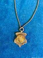 Close-up of the antique sterling silver pendant showing the football player medallion and detailed shield design.