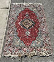 Full view of the Turkish handwoven carpet showing the central medallion, detailed floral motifs, and fringed edges, placed on asphalt background.