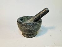 Granite mortar with pestle resting inside, showing size and texture of the set.