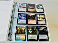 Photo of a three-ring binder opened to a page with nine Magic the Gathering cards displayed in protective sleeves, featuring mostly blue and black cards.