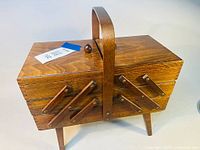 Front angle of the wood accordion expanding sewing basket closed with handle and legs