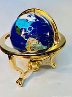 Front angle of a globe with a brass stand and built-in compass, showing the Americas side.