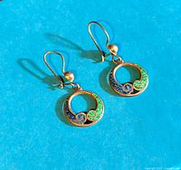 Pair of vintage 1950s sterling silver hoop earrings with blue and green lapis swirl detail photographed on a turquoise background under direct light to show color and condition.