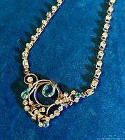 Close-up photo showing detailed pendant with sterling silver openwork swirl design and both clear and blue rhinestones.