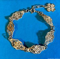 Full view of linked filigree sterling silver bracelet with toggle clasp and small flower charm.