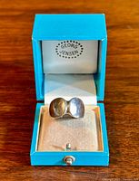 Ring centered in open teal box showing front profile of concave oval design and interior Georg Jensen logo