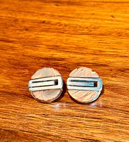 Front view of both clip-on earrings showing circular rosewood base with horizontal silver-tone G