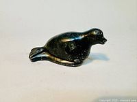 Front and side view of a dark green/black soapstone bird sculpture carving with polished finish, showing round body, beak, eyes, and flared tail.