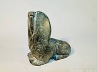 Side view of vintage Inuit soapstone sculpture depicting a walrus in a seated posture showing detailed flipper and facial features.
