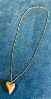 Full view of the heart pendant on the gold-filled sterling silver chain on a blue fabric background.