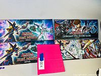 Four Yu-Gi-Oh! playmats laid out, three clearly showing Duel Power and Legendary Collection Kaiba themes, alongside a bright pink card album.