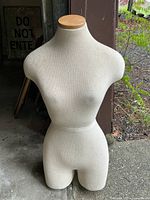 Front view of beige fabric-covered dress form mannequin torso showing feminine shape with wooden neck cap.