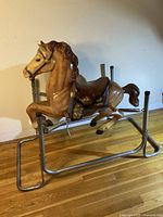 Right side view of brown plastic rocking horse on metal frame with spring base showing full profile and details of saddle and handlebars.