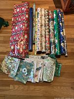 Overview of all wrapping paper rolls, flat sheets, and container on hardwood floor