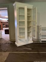 Full front view of white wooden cabinet with glass door open, showing shelves and drawer.