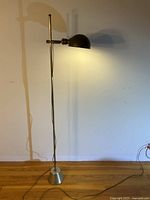 Full view of the floor lamp showing construction, weighted base, and the lamp lit on the side wall.