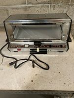 Front view of General Electric Deluxe Toast-R-Oven toaster oven showing controls, glass door, power cord and overall condition.