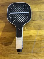 Front view of the shower head showing the black face with multiple nozzles and three control buttons on the handle.