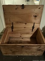 Open view of the wooden crate showing interior condition, metal hinges, and latch.