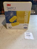 Box of 3M TaperFit 2 earplugs with product branding and size visible.
