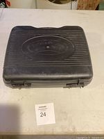 Closed black plastic carrying case with Coleman logo embossed on top, showing secure latches and compact size.