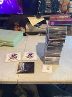 Stack of CDs and a 6-disc boxed set visible on table, with two 15 year anniversary stickers nearby