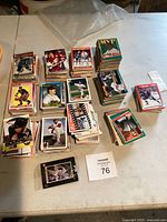 Multiple stacks of collectible hockey and baseball cards on a white table, showing various players and card designs