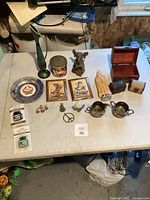 Full view of all items on table showing variety of collectibles and home decor items including figurines, box, plaques, and small items.