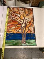 Photo showing full stained glass panel with tree design and copper detail, measuring tape included for scale showing approximately 25 inches in height.