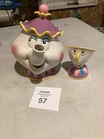 Ceramic teapot and cup designed as Mrs. Potts and Chip from Beauty and the Beast, showing front faces and details.