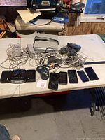 Full view of the lot with Nintendo Wii accessories, smartphones, and numerous cables and adapters on a table.
