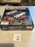 Box of wooden 3 game set showing chess pieces and board, with storage compartments for game pieces inside.