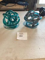 Two glass art sculptures side by side on a white surface, showcasing their shapes and color difference.