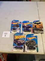 Lot of five Hot Wheels die-cast cars still in packaging arranged on a table.