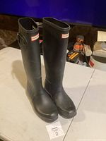 Front angled view of black Hunter boots showing logo and adjustable strap on side