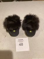 Front view showing the pair of black kids moccasins with dark fur trim and multicolored bead decoration on toe area.