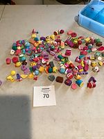 Image showing a large group of small pencil toppers on a table, featuring various colorful and whimsical designs including food and character shapes.